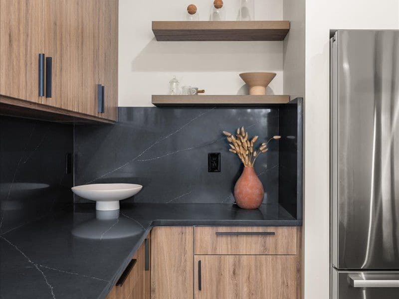 A kitchen with black marbled countertops and medium brown cabinets.